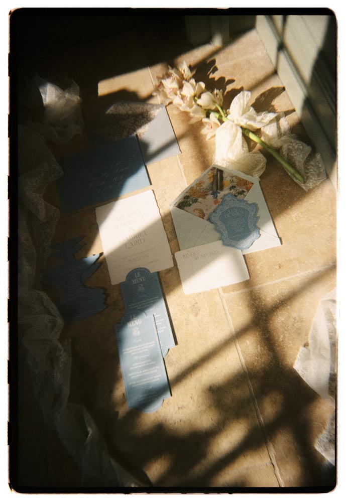 Analog-Foto: Papeterie und Blumen liegen im Sonnenlicht auf einem Tisch.